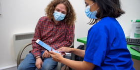 A nurse holding an ipad showing it to a male